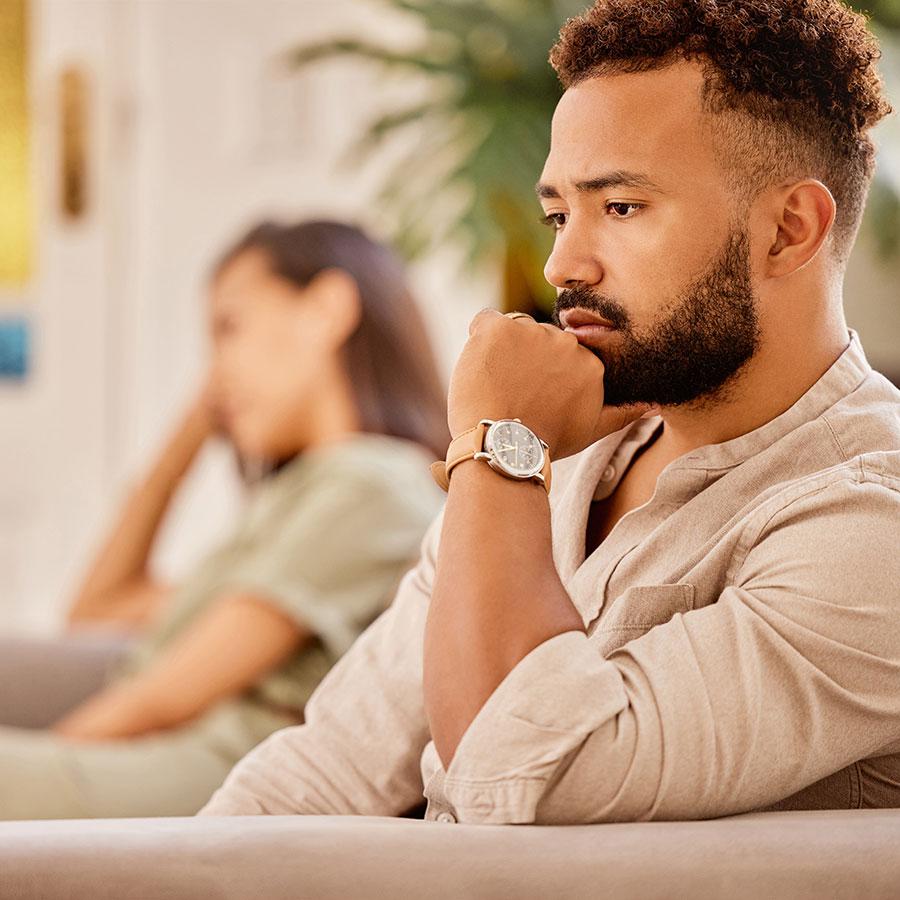 An unhappy couple sitting apart on a couch, both looking away with expressions of frustration and sadness near Chicago